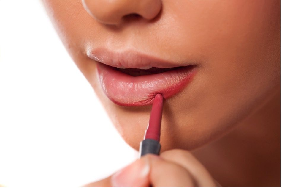 A close-up of a person applying lipstick