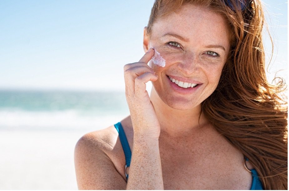 A person applying sun cream on her face